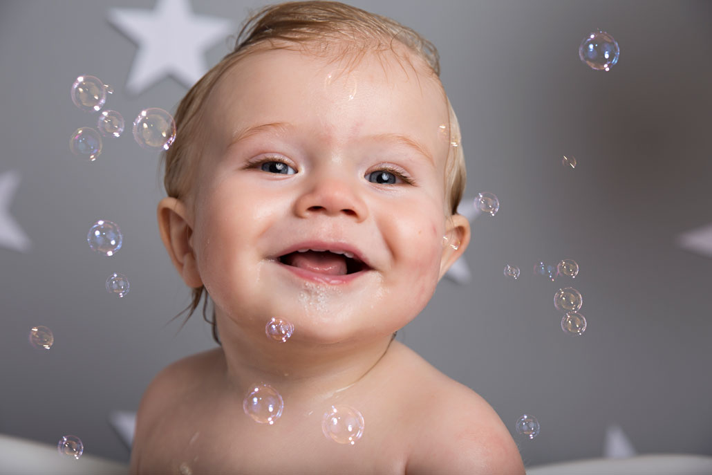 cake smash photographer ipswich baby with bubbles on face smiling cake smash photographer ipswich baby with bubbles on face smiling