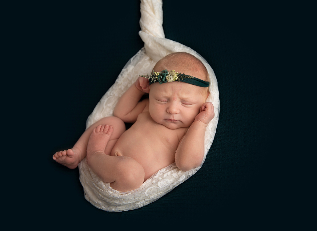 newborn photography ipswich baby in white wrap on green background with headband newborn photography ipswich baby in white wrap on green background with headband